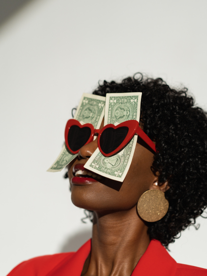 Frau mit roter Sonnenbrille und Geldscheinen dahinter